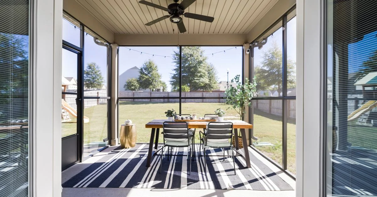 Una terraza brillante y acogedora con mesa de comedor y sillas, con vistas a un jardín soleado.