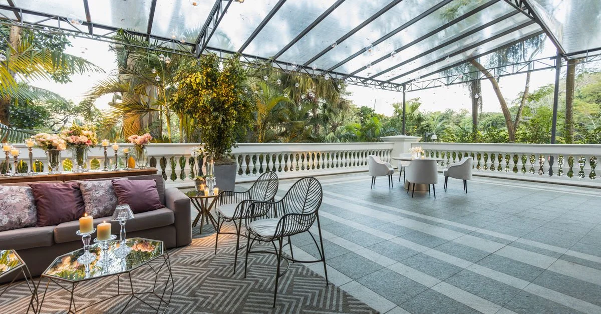 Terraza exterior bellamente diseñada con asientos elegantes bajo un techo de vidrio.