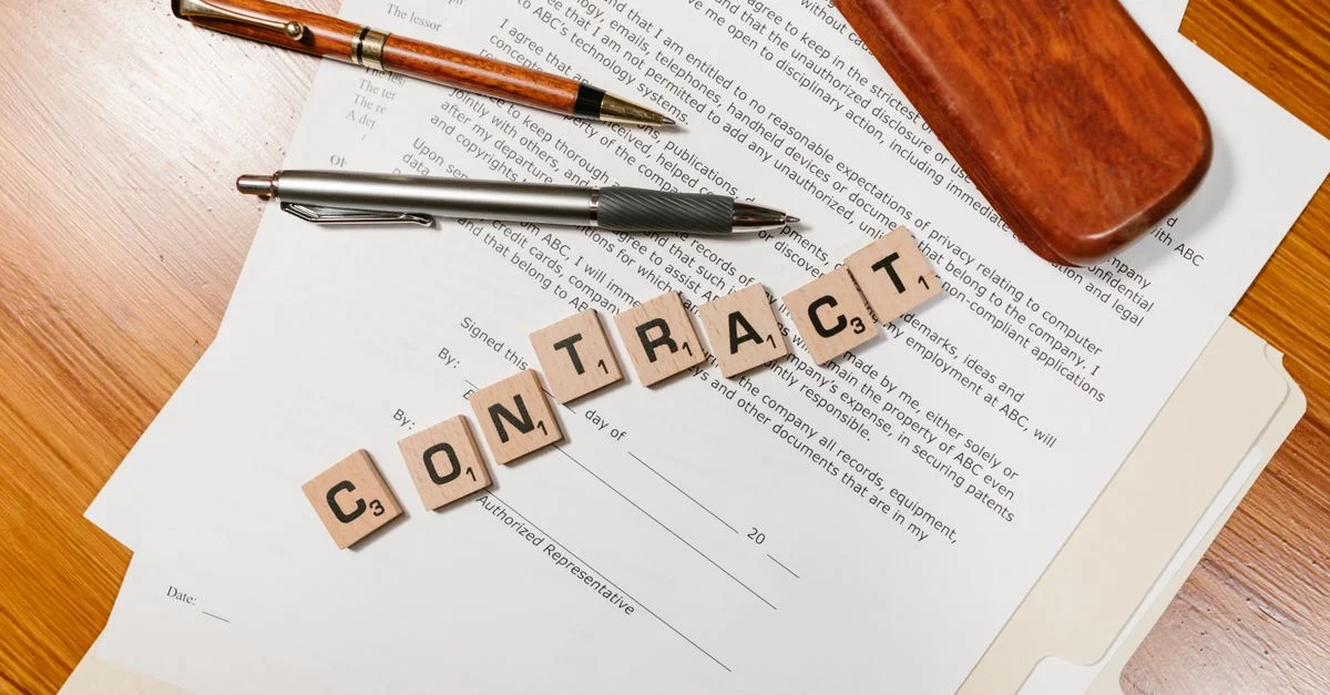 Primer plano de documentos de contrato con fichas de Scrabble que deletrean 'CONTRATO'.