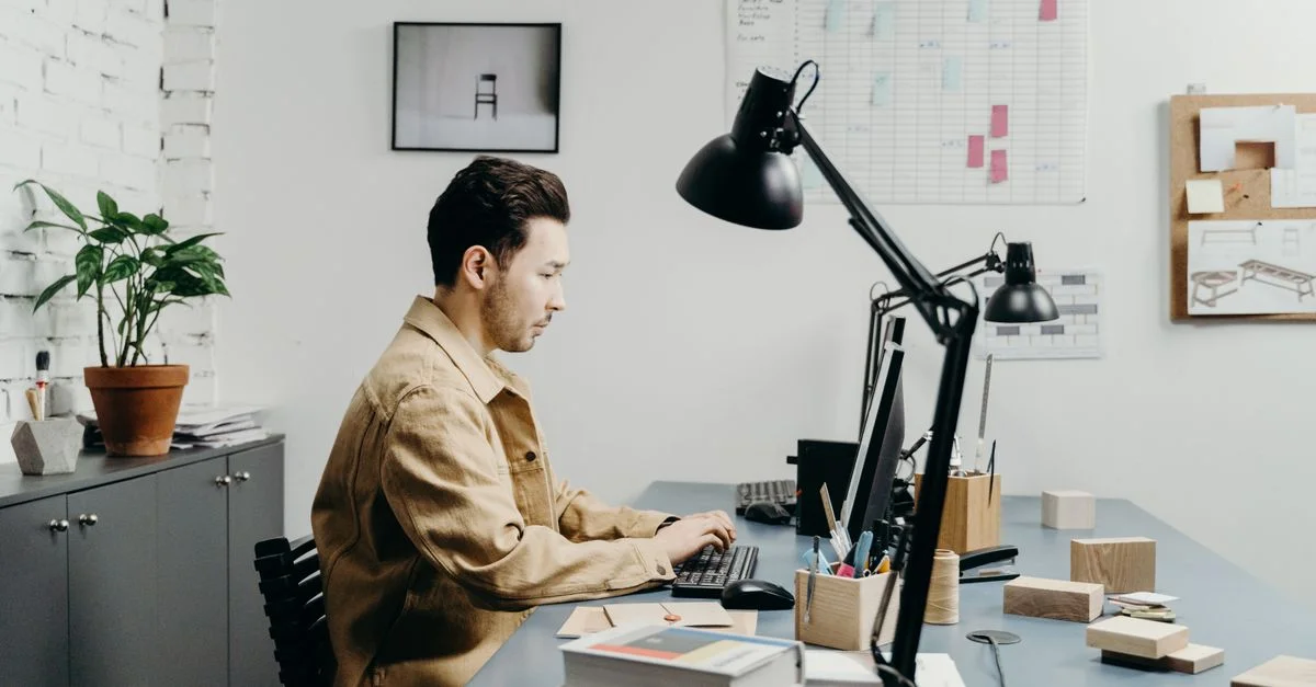Hombre trabajando en una computadora en un entorno de oficina moderno con espacio de trabajo organizado.