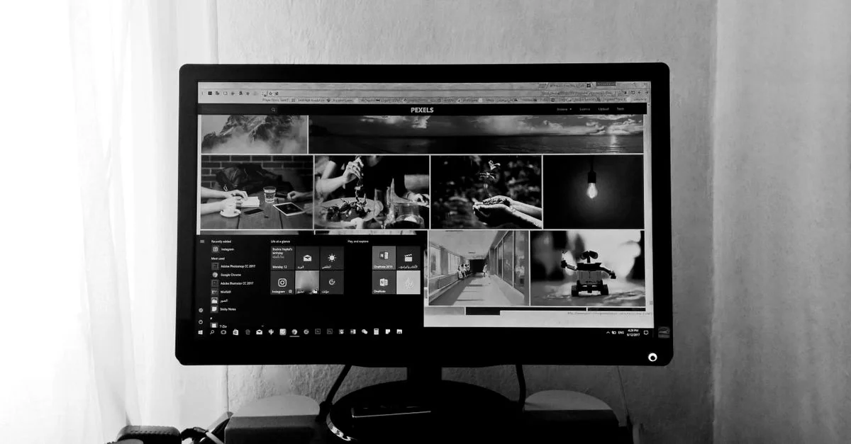 Una foto en blanco y negro de un monitor de computadora que muestra varias imágenes y aplicaciones en un entorno interior.