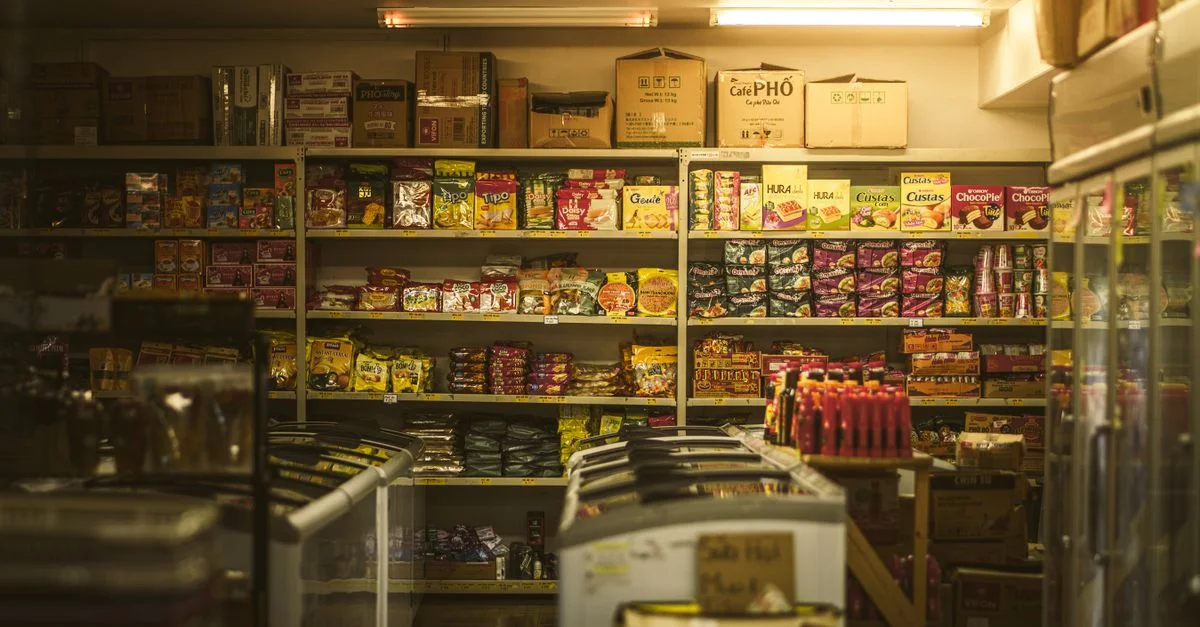 Estantería repleta de diversos snacks y comestibles asiáticos en un entorno de tienda acogedor.